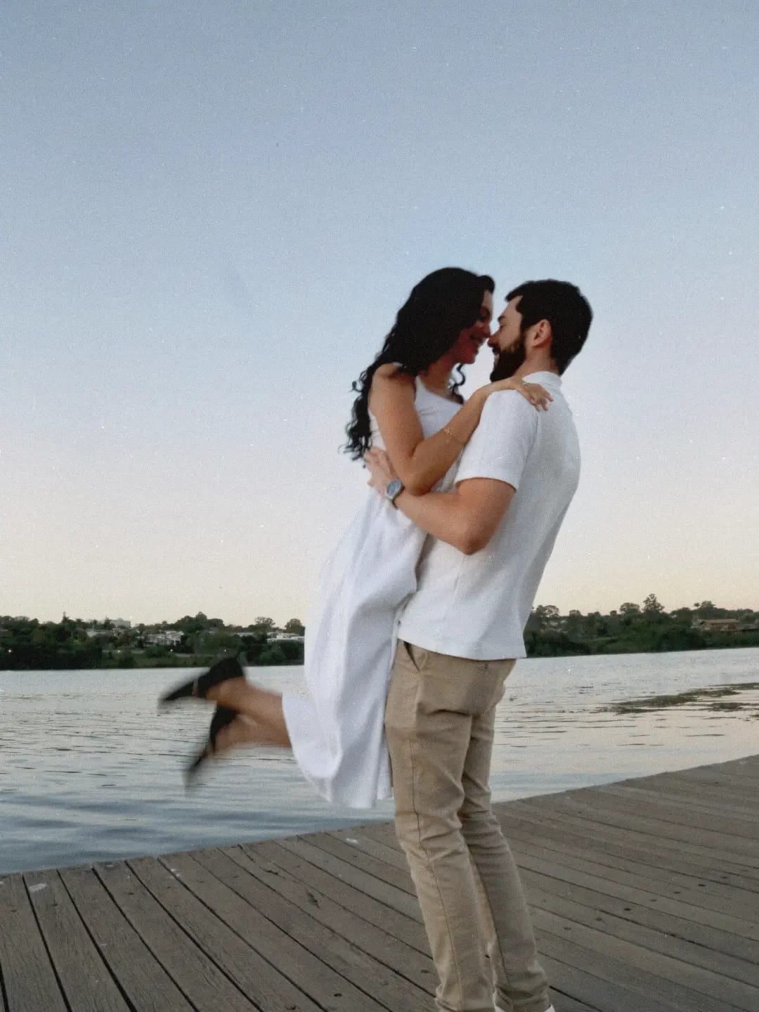 Felipe levanta Layla no deque, à beira do lago